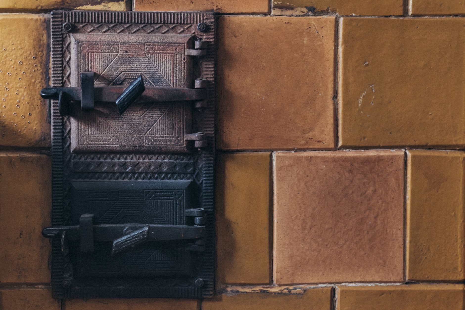 Close-up of a vintage iron latch on a rustic tan brick wall, showcasing aged texture and detail.