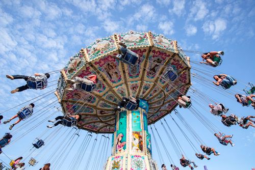 Free People enjoying a vibrant swing ride under a clear blue sky at a fair in Toronto. Stock Photo