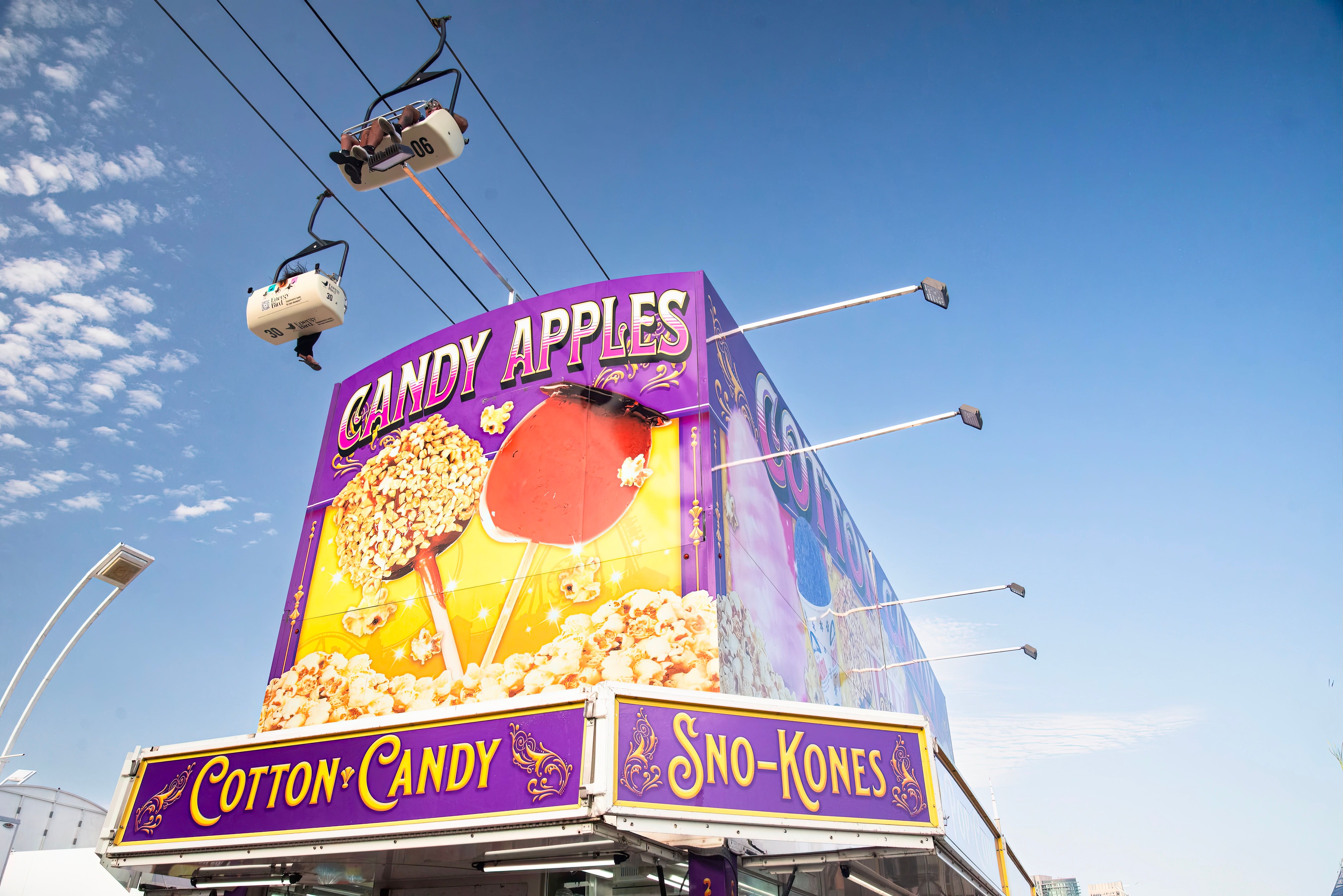 Colorful candy apples and sno-kones stand under blue sky at Toronto fair.