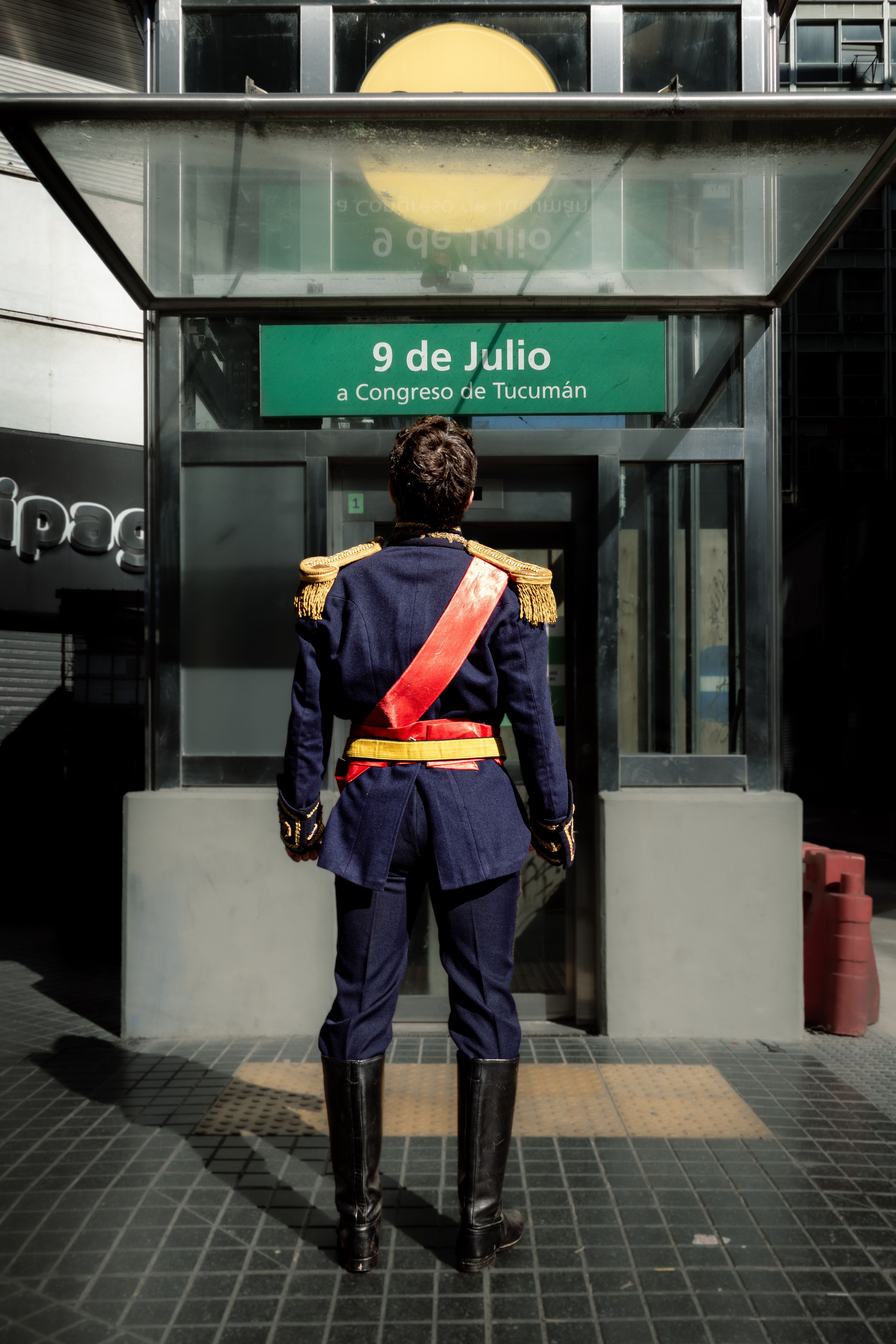 Person in historic military uniform standing at 9 de Julio subway entrance in Buenos Aires.