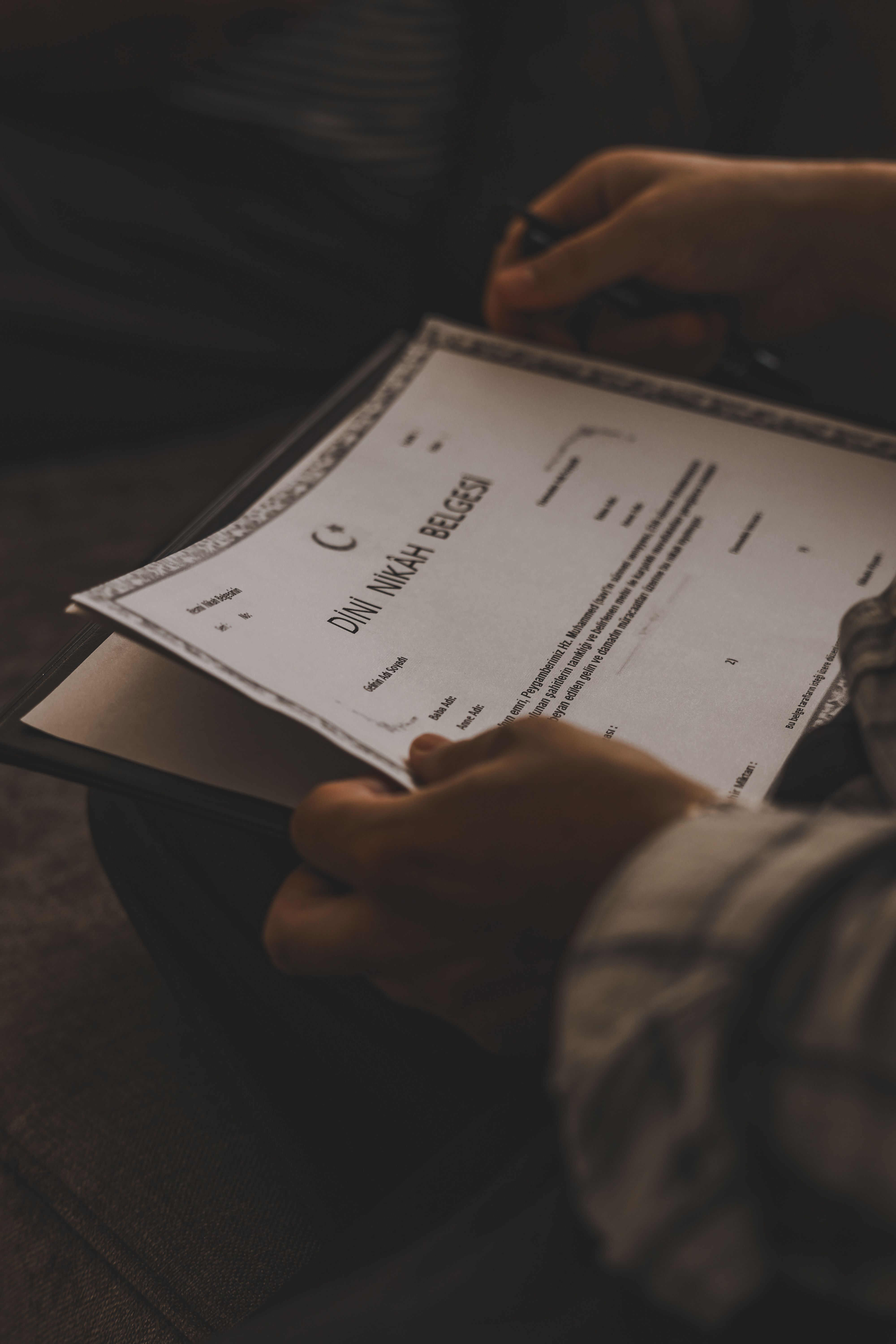 A person holding a legal document in a dimly lit setting, conveying formality and focus.
