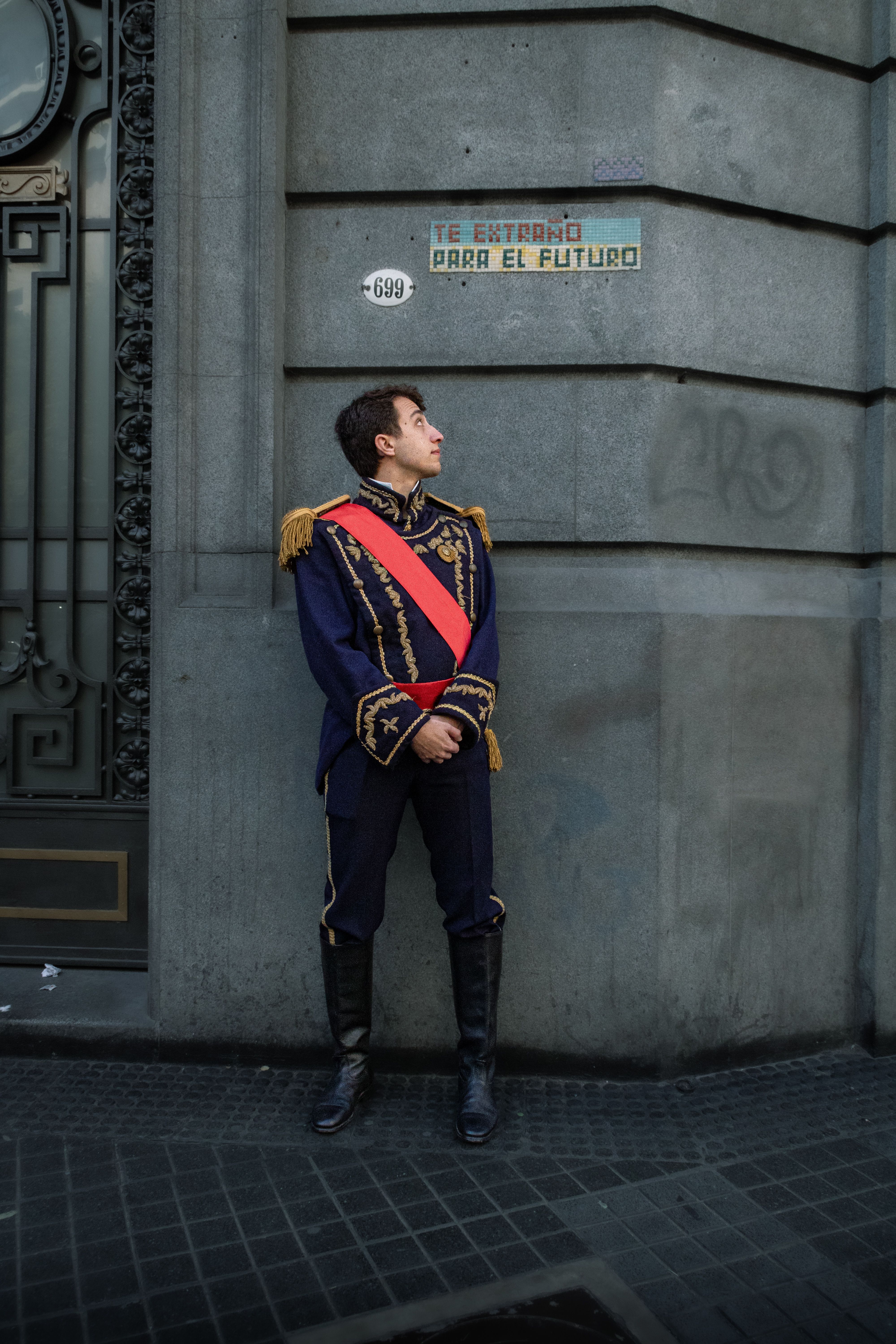 Man in traditional Argentine historical uniform standing by a wall in Buenos Aires.