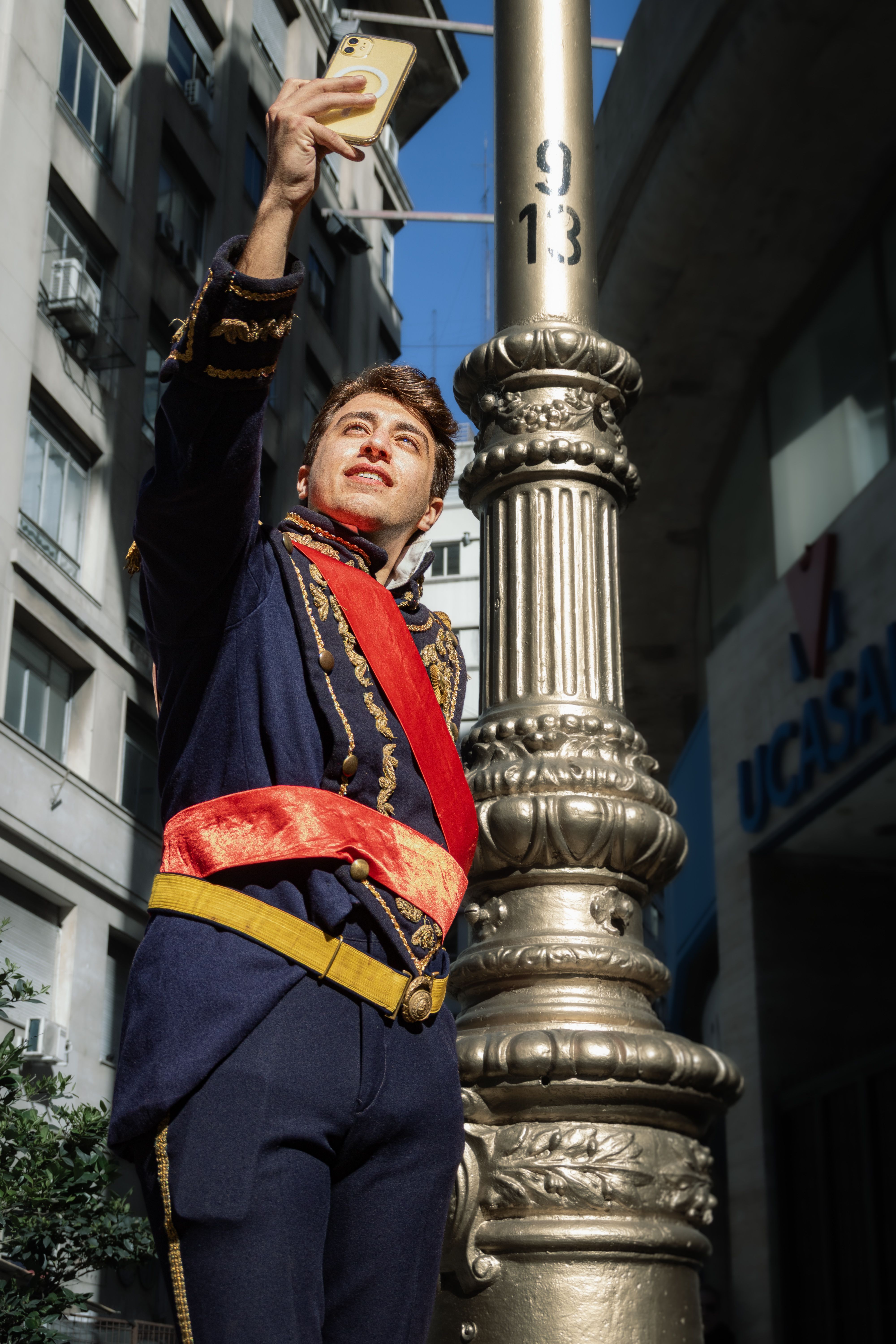 Man in historic costume taking a selfie in Buenos Aires street, daytime.