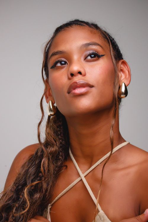 Free Beautiful portrait of a woman with braided hair and gold earrings, looking thoughtfully upward. Stock Photo