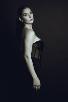 Artistic black-and-white portrait of a woman in a corset, showcasing elegance.