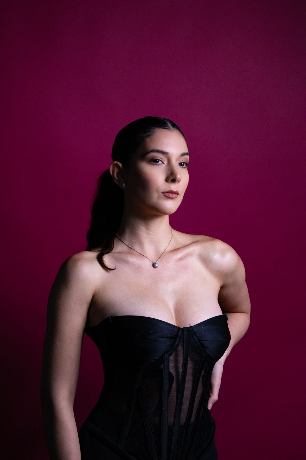Portrait of a woman in a black dress on a pink backdrop