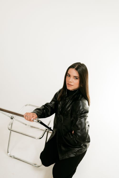 Free Portrait of a stylish woman in a leather jacket with a minimalist background. Stock Photo