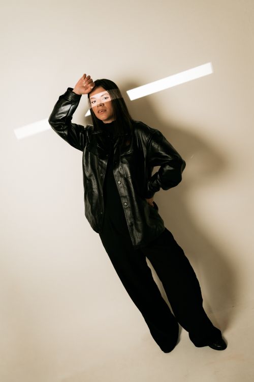 Free Stylish woman poses in a black leather jacket with dramatic lighting. Stock Photo