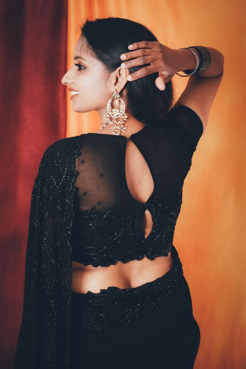 Free Stylish portrait of a woman in a black saree, showcasing intricate jewelry and a graceful pose. Stock Photo