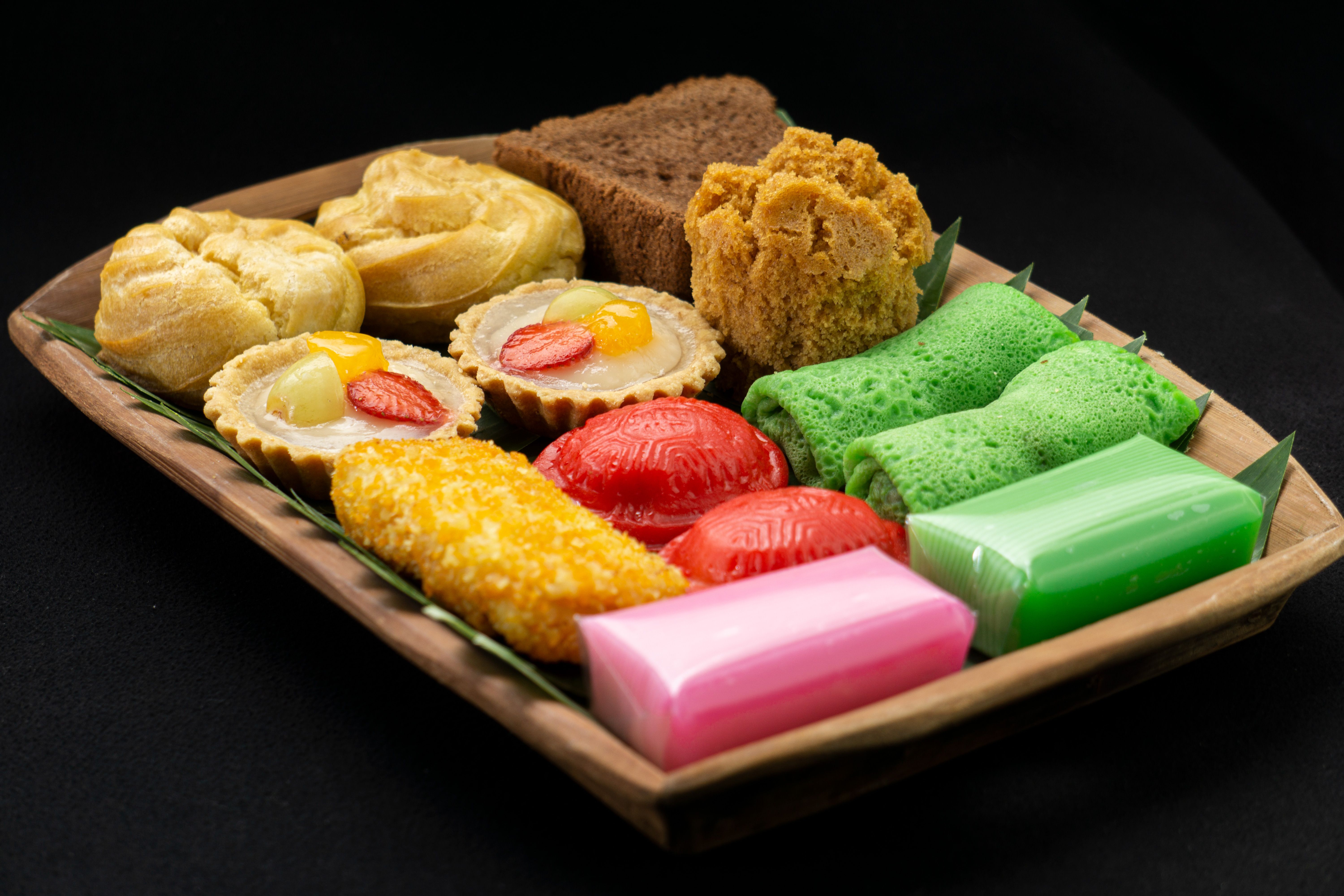 A plate of colorful Indonesian traditional snacks displayed on a wooden tray in Jakarta.