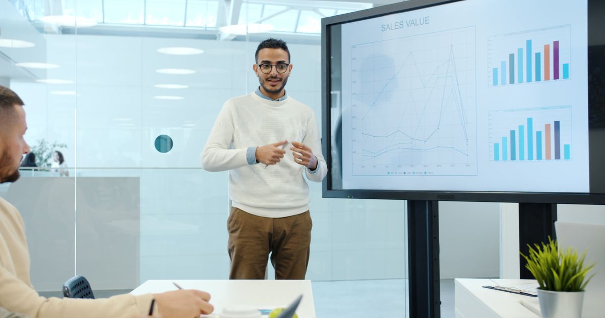 Professional delivering a business presentation with charts in a modern office.