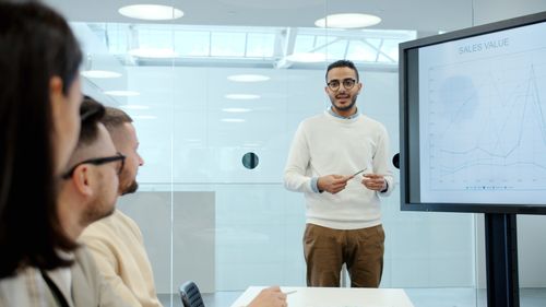 Free Professional presenting sales data on screen during office meeting. Stock Photo