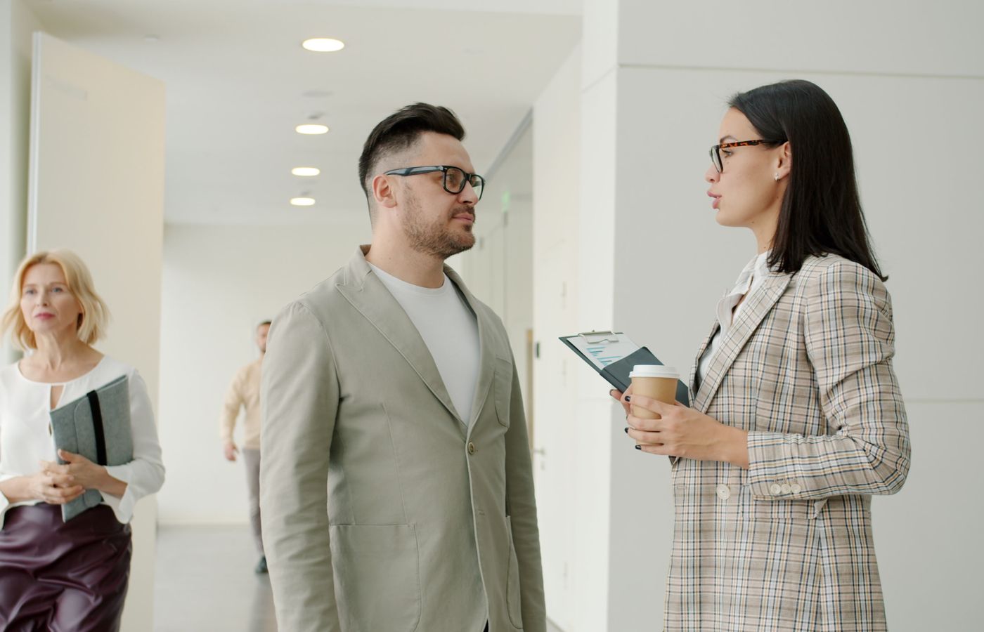 A group of business professionals engaged in conversation in a modern office space.
