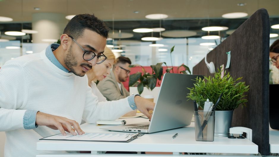 Equipo diverso de profesionales que trabajan diligentemente en un entorno de oficina moderno y abierto.