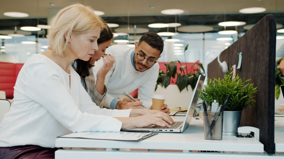 Miembros del equipo colaborando en un entorno de oficina moderno, intercambiando ideas.