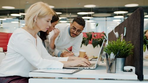 Free Team members collaborating in a modern office setting, brainstorming ideas together. Stock Photo