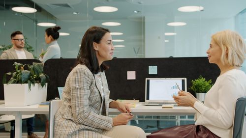Free Two women engage in a business discussion at a modern office workplace. Stock Photo