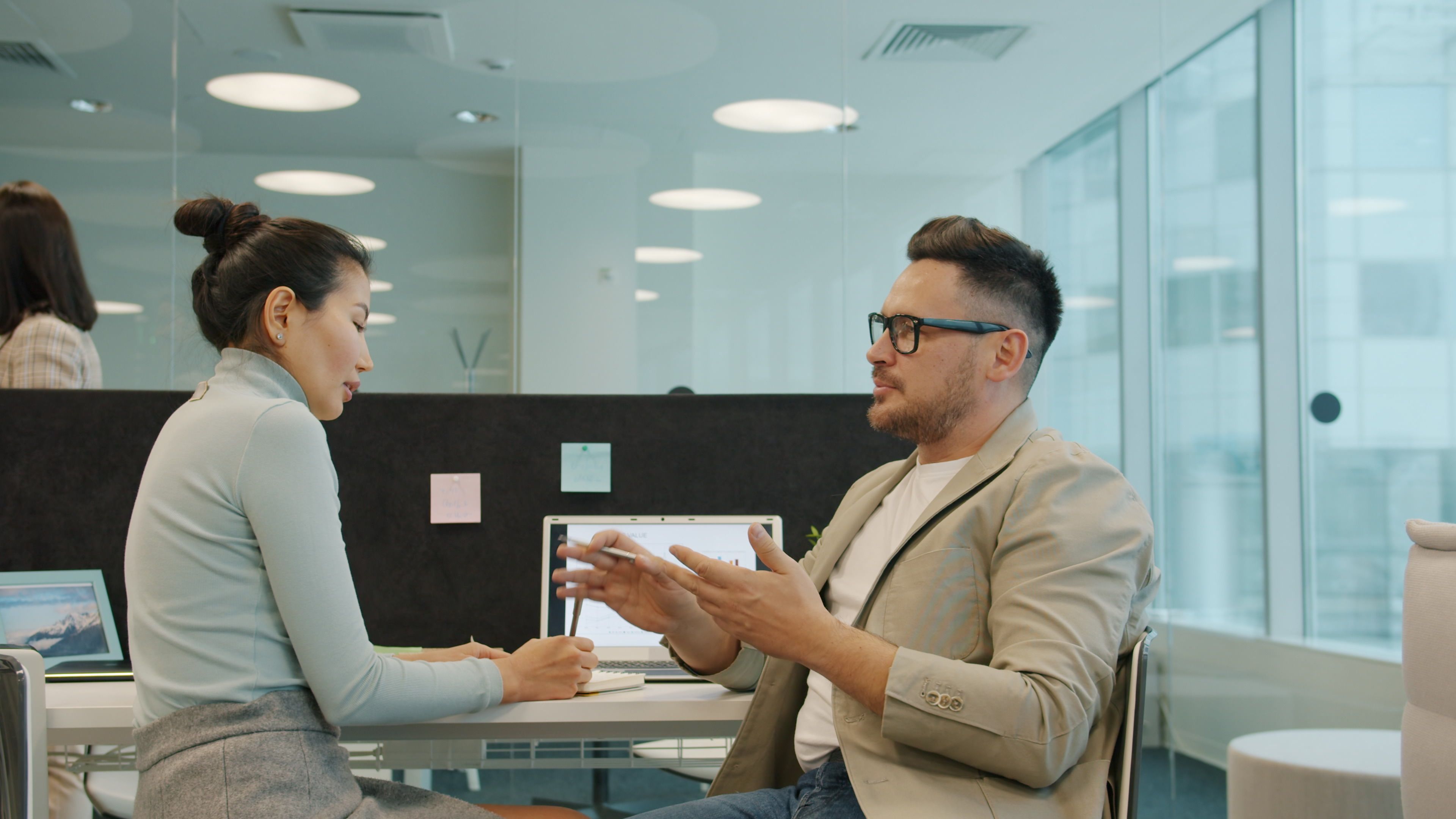 Two professionals engaged in a conversation in a modern office setting.