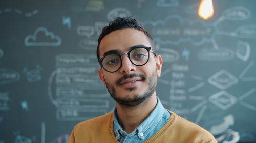 Free Portrait of a young professional man in an office setting with a creative brainstorm background. Stock Photo