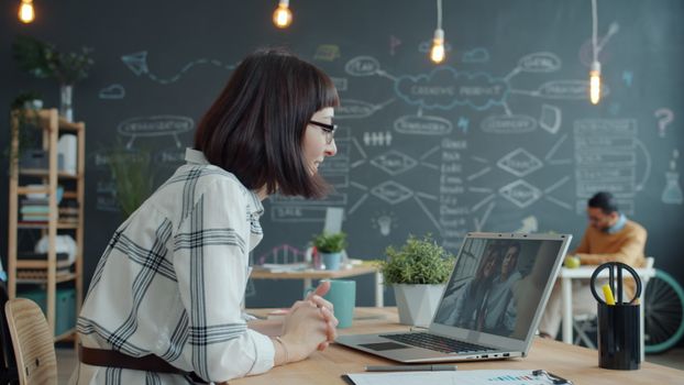 Businesswoman engaging in video call in a modern office setting with creative decor.
