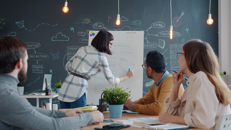 Grupo de compañeros colaborando en un proyecto en una sala de reuniones creativa.