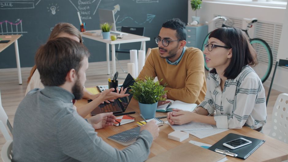 Un grupo de jóvenes profesionales intercambiando ideas en un entorno de oficina contemporáneo.