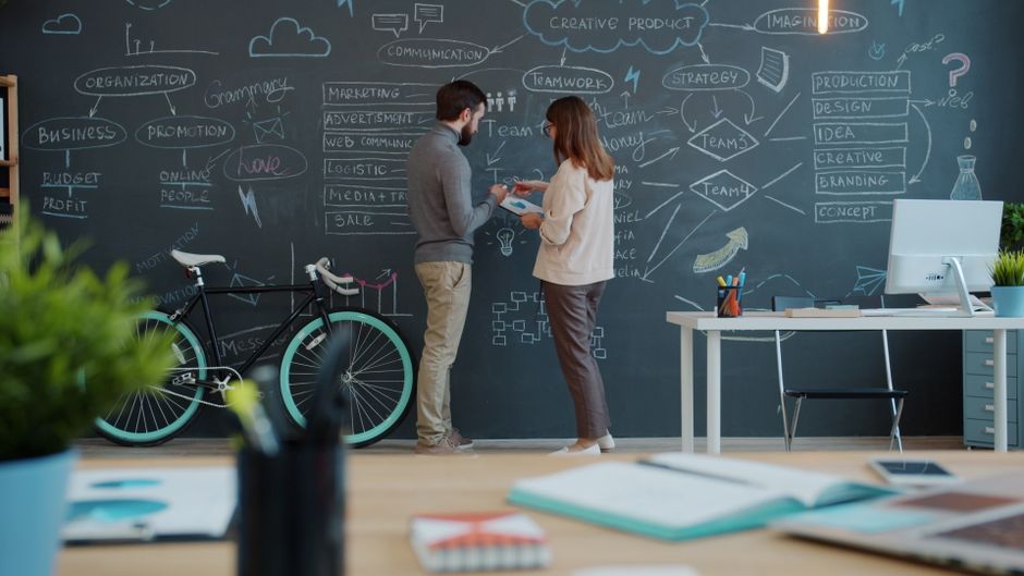Los miembros del equipo intercambian ideas innovadoras en una pizarra en un espacio de oficina dinámico.