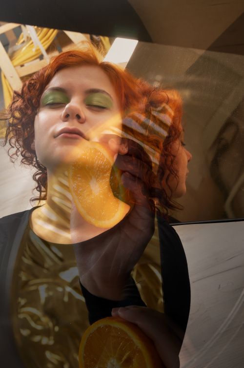 Free Creative portrait of a woman with red hair and orange reflection in a mirror. Stock Photo