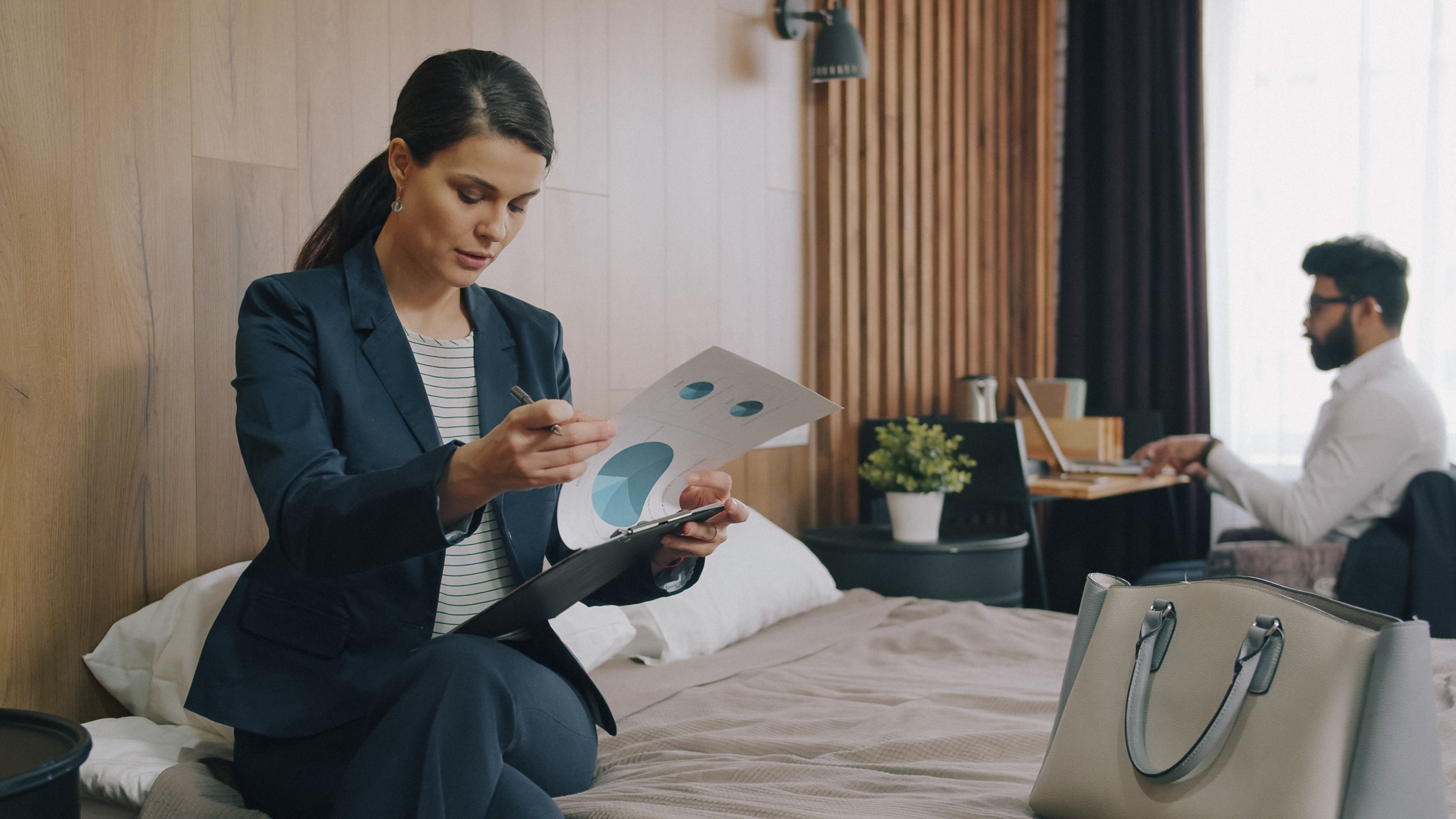 Professionals working on laptops in a stylish hotel room, reviewing documents.