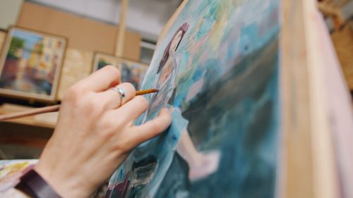 Free A painter's hand working on an oil painting, captured close-up in an art studio. Stock Photo