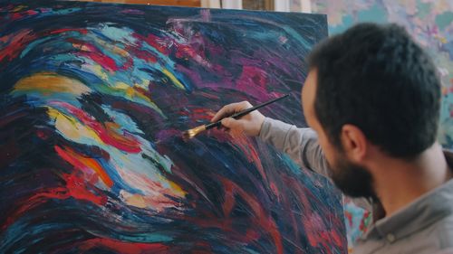 Free An artist creating a colorful abstract painting in a studio setting. Stock Photo