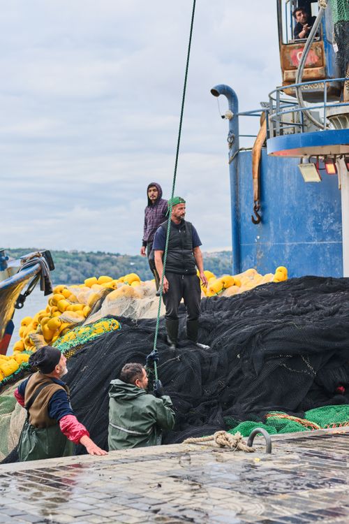 Free A group of fishermen working on nets in Beykoz, İstanbul. Vibrant harbor scene. Stock Photo