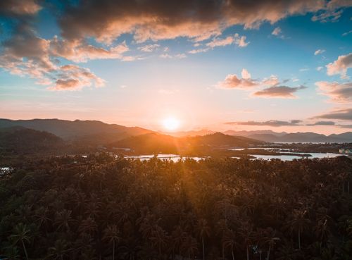 Free Captivating aerial view of a sunset over a tropical forest and mountain landscape. Stock Photo