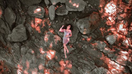 Free Aerial shot of a woman in a dress lying on a rocky surface with dramatic lighting effects. Stock Photo