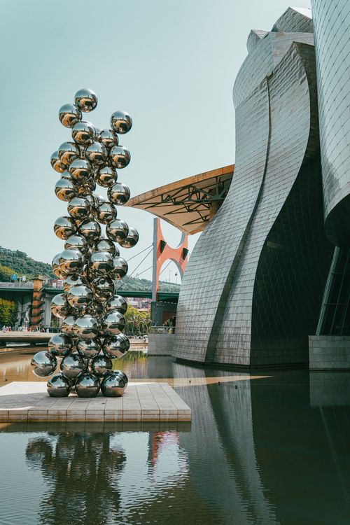 Free Sculpture and curving architecture reflect in water at the Guggenheim Museum in Bilbao. Stock Photo