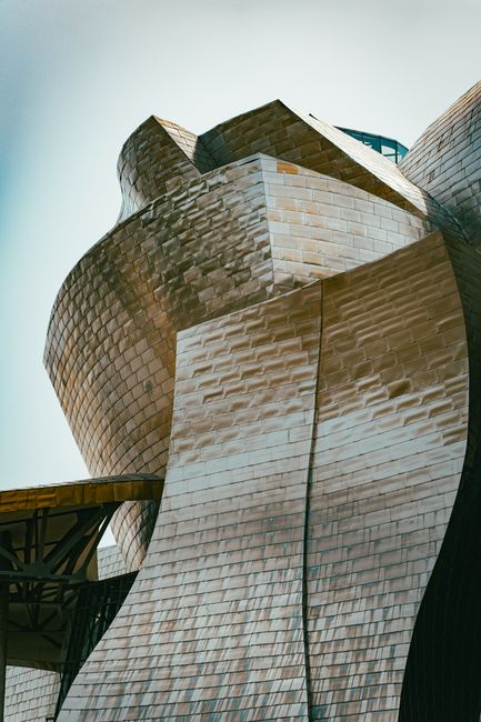 Fotomural Una vista impactante de la arquitectura moderna, con formas geométricas y superficies metálicas en un entorno urbano.