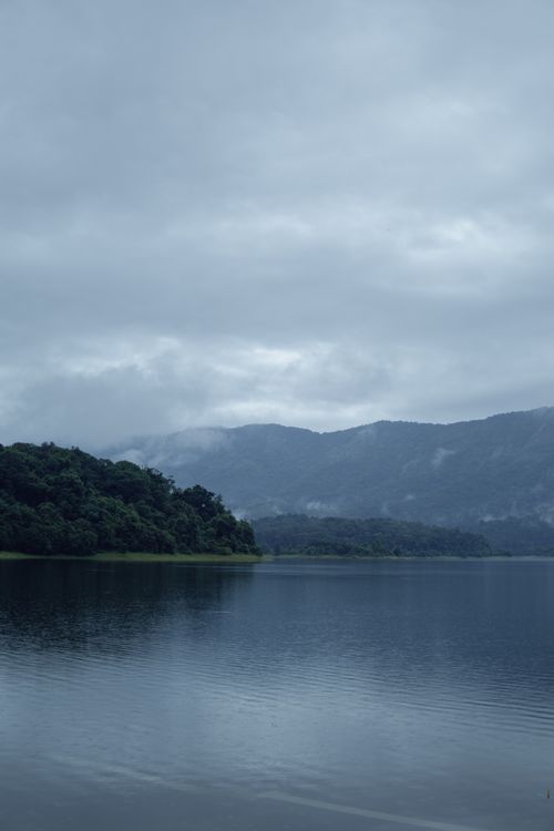 Free Peaceful landscape of a lake with misty mountains and lush greenery in Pariyaram, Kerala, India. Stock Photo