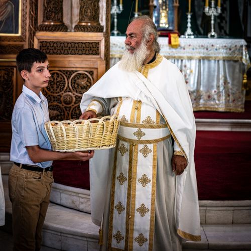 Free A Greek Orthodox priest in traditional attire conducts a ceremonial offering with a young assistant. Stock Photo