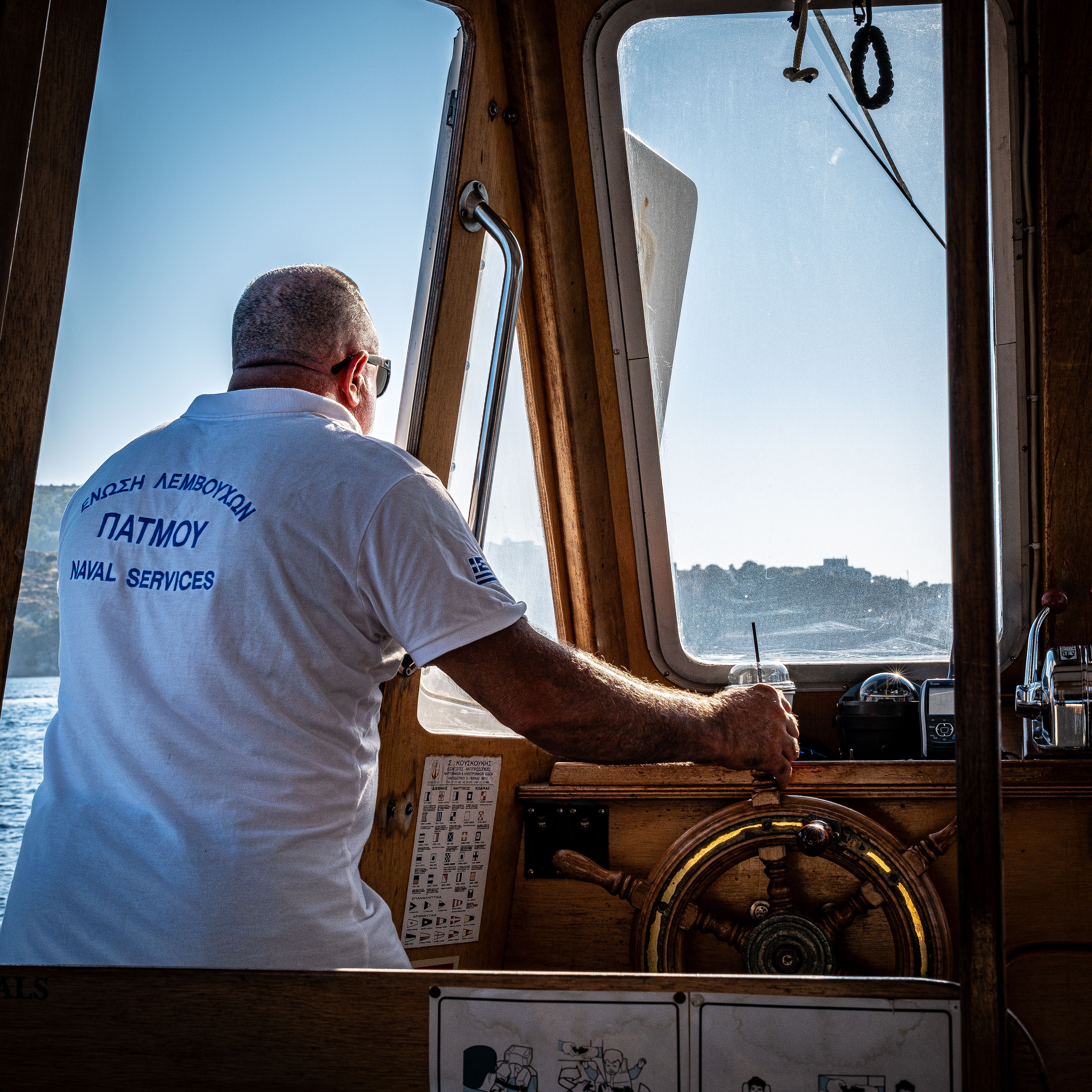 A captain navigating a boat through Greek waters, showcasing maritime tradition and scenic views.