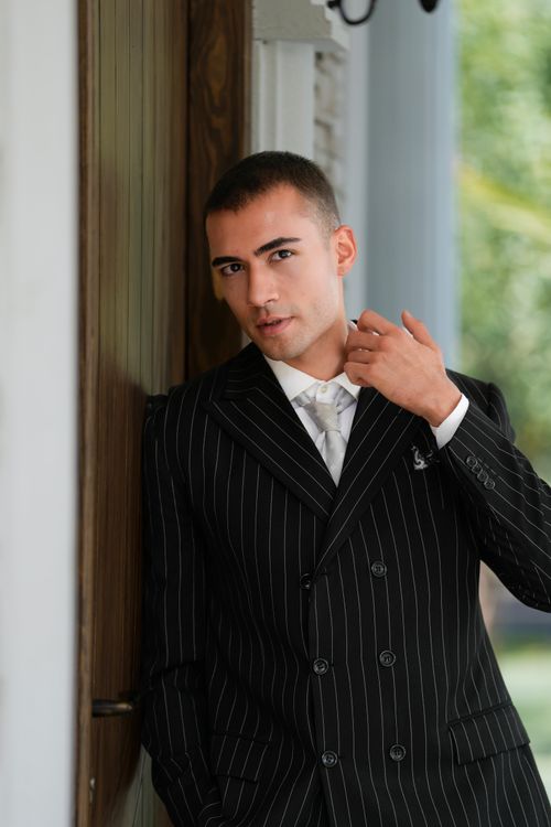 Free Sharp dressed man in a pinstripe suit leaning casually outdoors. Stock Photo
