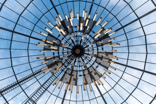 Free Upward view of a modern glass dome ceiling with intricate design against a blue sky. Stock Photo