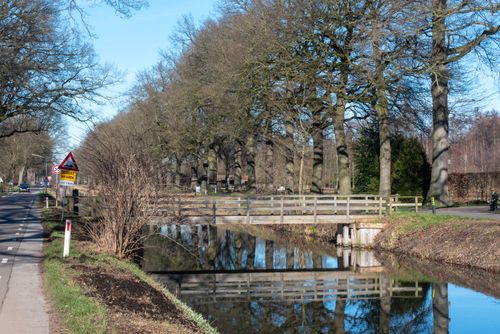Free Tranquil canal scene in Helenaveen, Netherlands, featuring a wooden bridge and bare trees in winter. Stock Photo