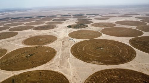 Free Aerial shot of circular irrigation patterns in an arid desert landscape. Stock Photo