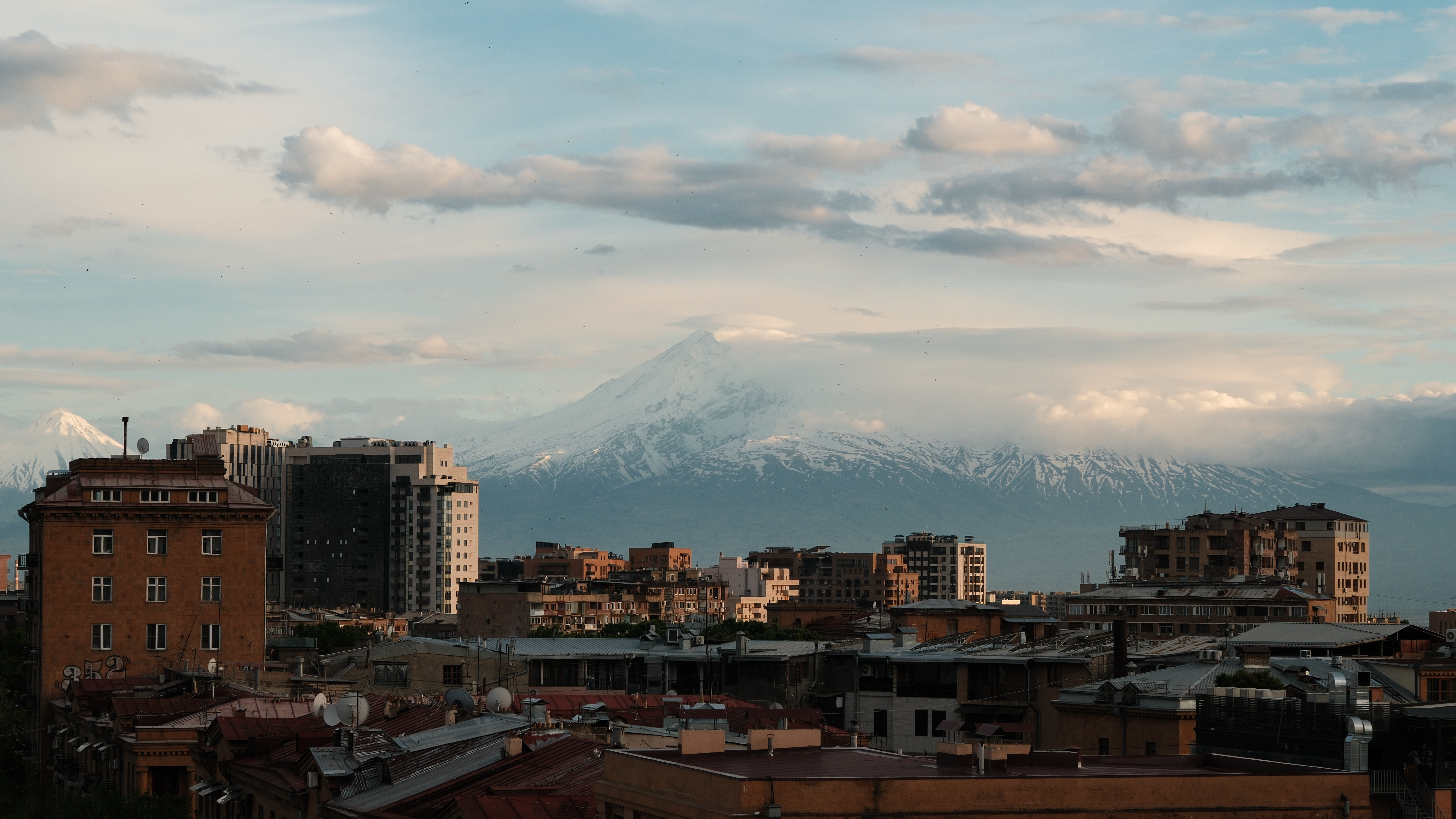 Discover a stunning view of snowy Mount Ararat rising above Yerevan's urban landscape.