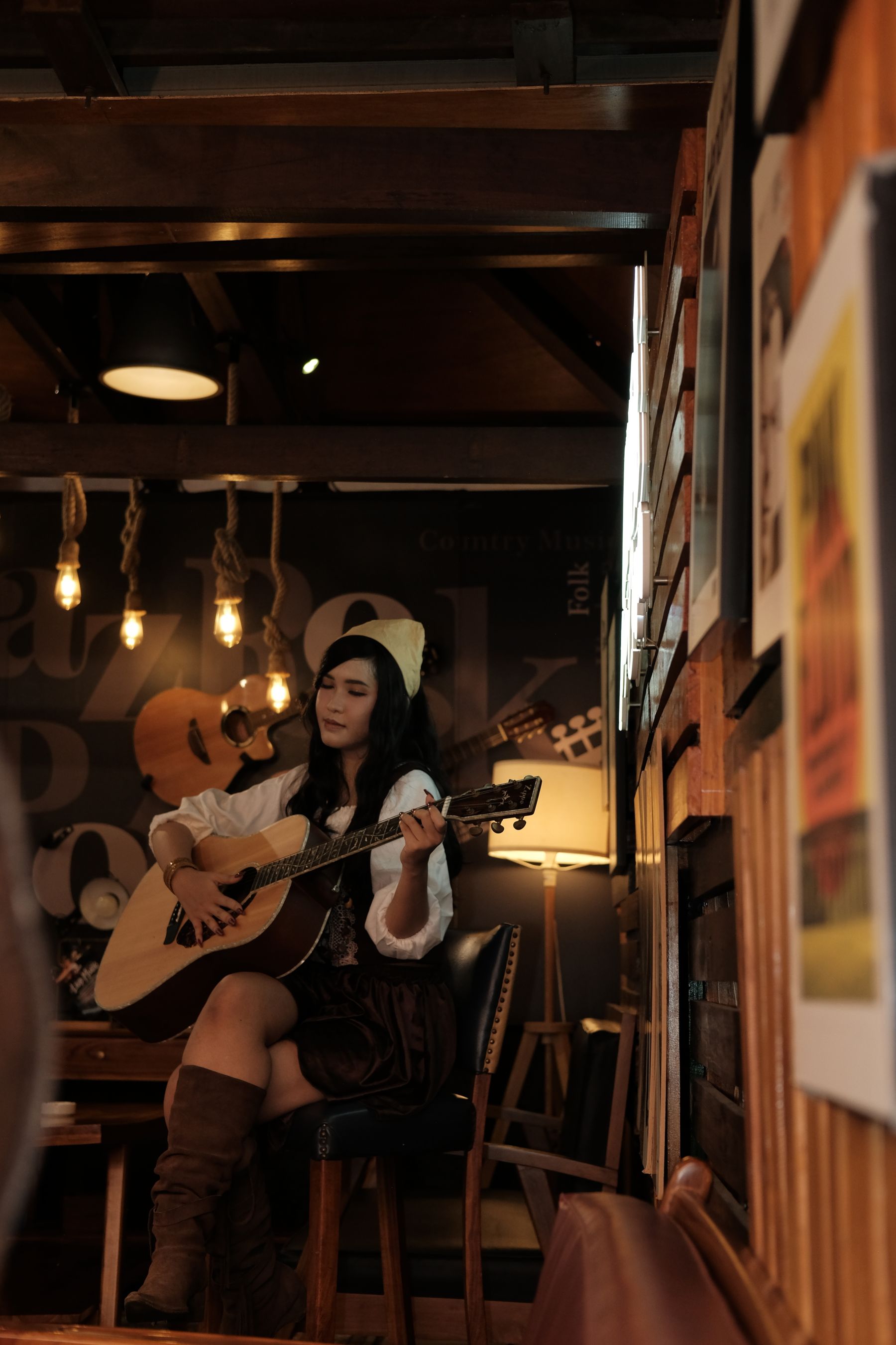 A singer with an acoustic guitar performing in a warmly lit room