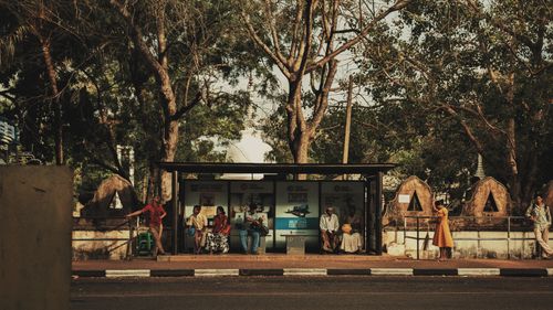 Free A busy bus stop in Anuradhapura, Sri Lanka, with people waiting amidst lush trees and vibrant life. Stock Photo