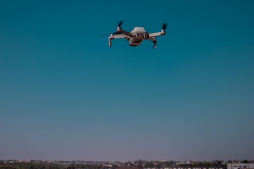 Free A drone captured mid-flight against a clear blue sky, illustrating modern aerial technology. Stock Photo