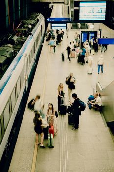 A busy train station in Poland with travelers and commuters captured from above, showcasing hustle and bustle.