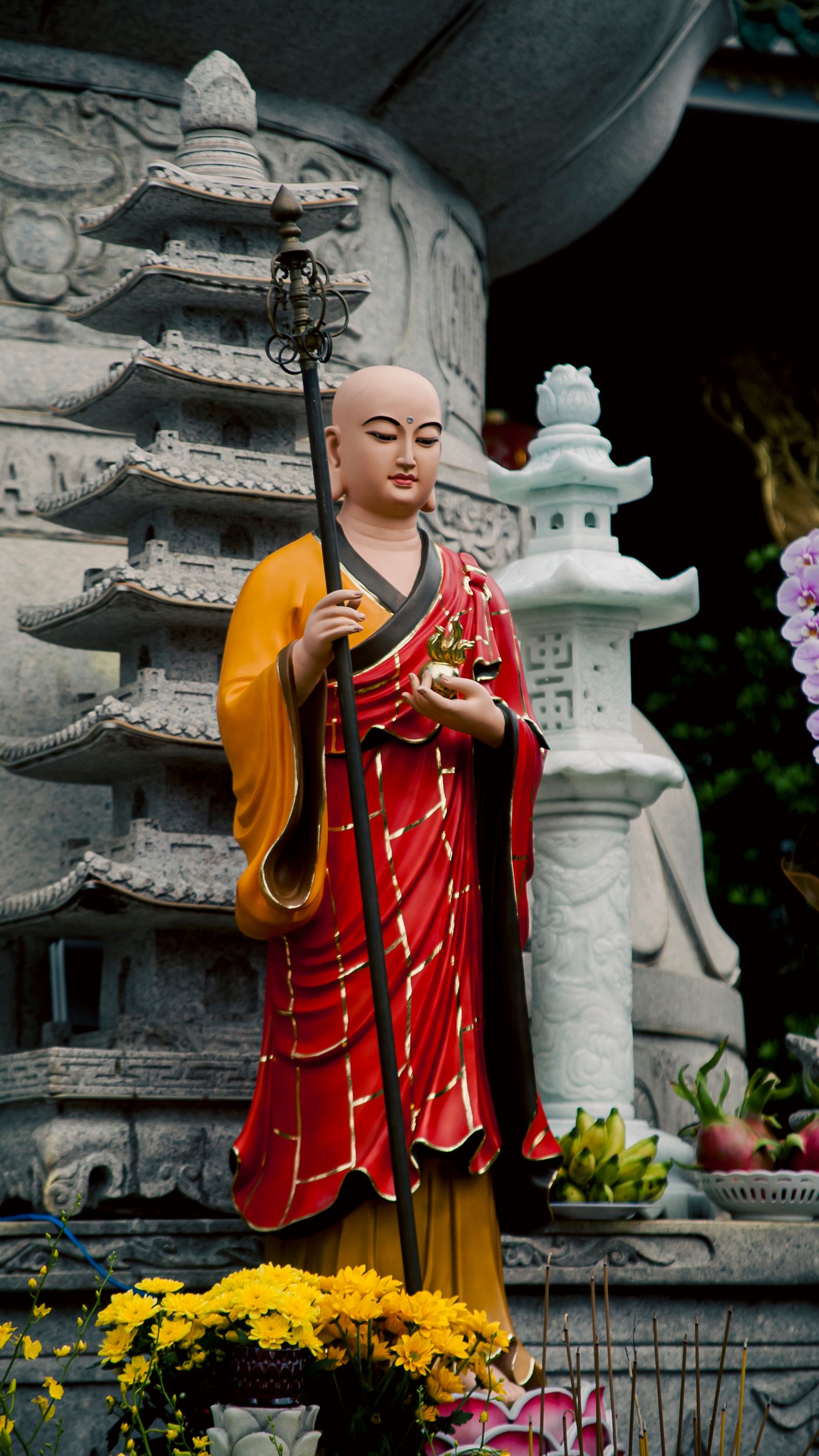 A detailed Buddhist monk statue with a pagoda background in Ho Chi Minh City, Vietnam.