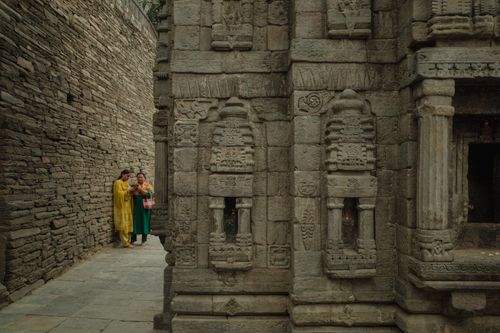 Free Two adults in colorful attire explore intricate stone carvings of ancient architecture outdoors. Stock Photo